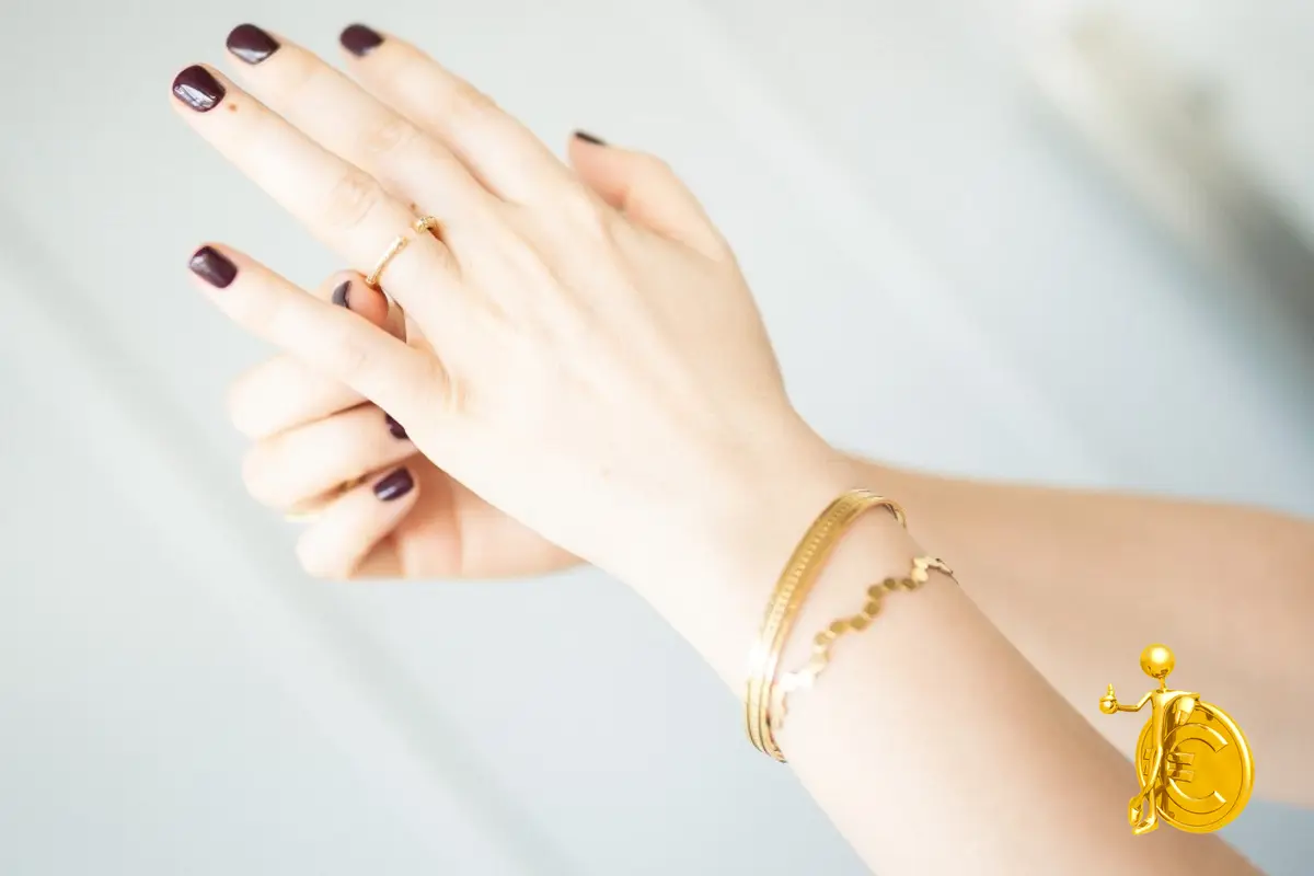 Una mano con un bracciale e un anello d'oro lucidi, luce naturale chiara
